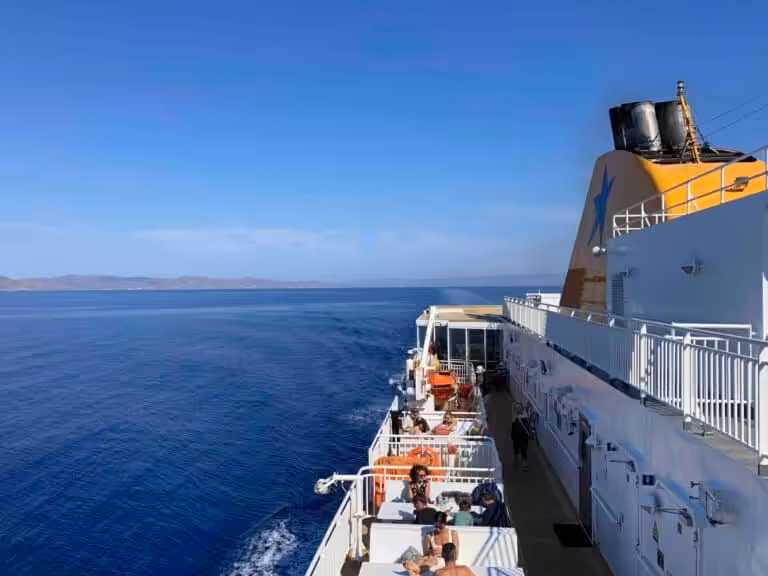 Ferry near the coast of Naxos, Greece, sailing across the deep blue sea with the island in the background.