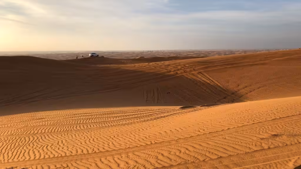 Vast dune landscape in the Dubai desert at sunset, with smooth sand waves and golden tones.