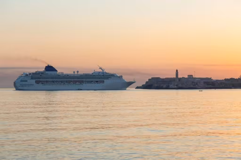 Luxury cruise ship sailing at sunset along a scenic coastline.