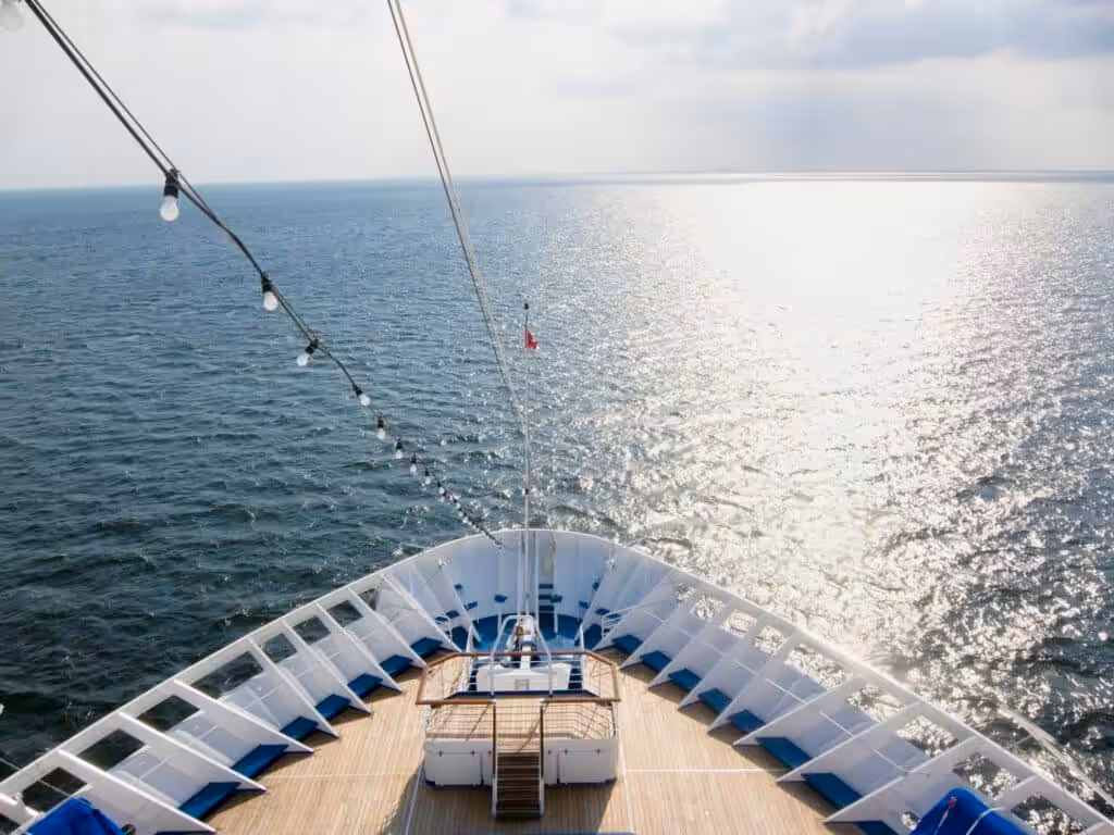 Bow of a modern cruise ship sailing on calm blue sea under clear sky
