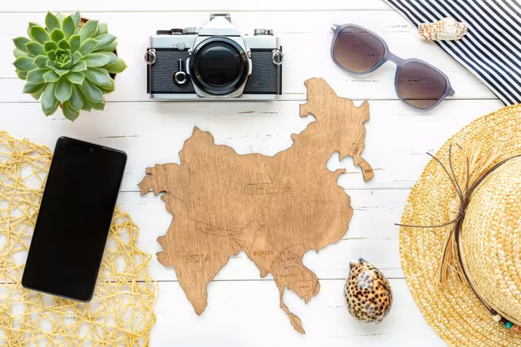 Travel accessories arranged around a wooden world map on a white table