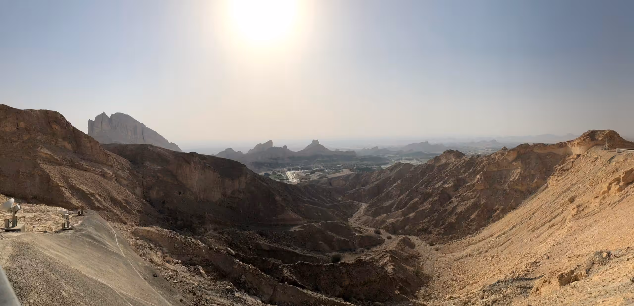 View from Jebel Hafeet in sunlight, overlooking the rocky landscape and surroundings of Al Ain.