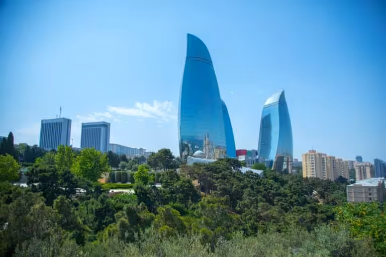 View of the Flame Towers in Baku from the seafront near Milli Park, with the Caspian Sea and promenade in the foreground.