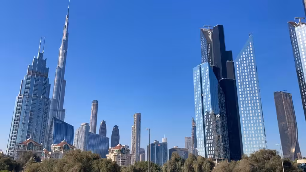 Modern city skyline with tall glass skyscrapers and blue sky in the background.
