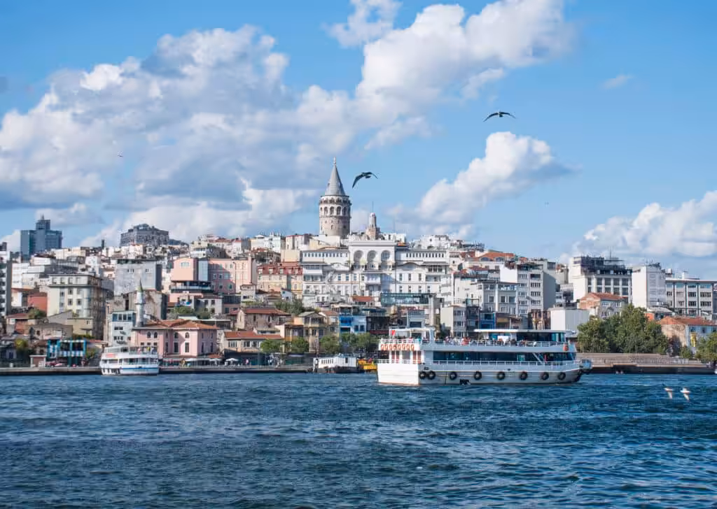 Istanbul skyline with Galata Tower overlooking the Bosphorus, boats on the water and historic buildings along the shore