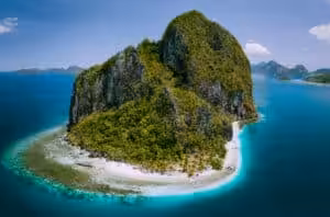 Aerial view of limestone island with white sand beach and turquoise water in El Nido, Palawan