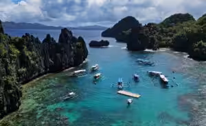 Traditional outrigger boats anchored in a turquoise lagoon surrounded by limestone cliffs in the Philippines