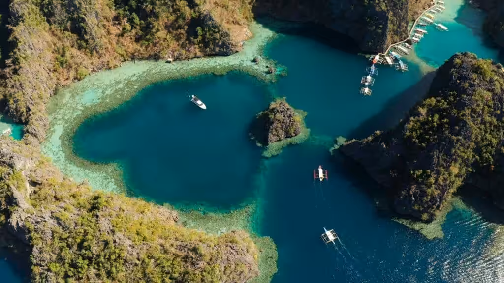 Aerial view of turquoise lagoon with boats and limestone cliffs in the Philippines