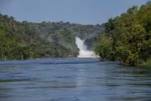 Wide river leading toward a distant waterfall framed by lush green forest