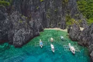 Traditional Filipino outrigger boats in a hidden lagoon with emerald water and limestone cliffs in Mindoro